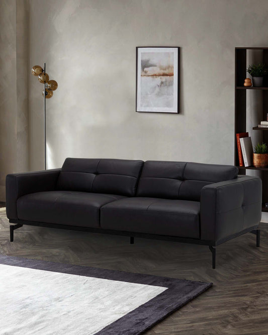 Sleek black leather sofa with modern design, paired with a decorative floor lamp and minimalist bookshelf in a stylish setting.