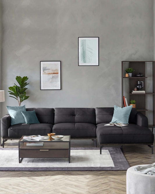 Modern living room featuring a black sectional sofa with teal accents, a glass-top coffee table, and a contemporary shelf unit.