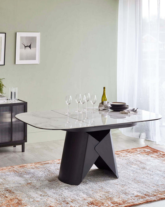 Modern round dining table with a marble top, black sculptural base, complemented by elegant glassware and stylish plates.