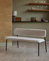 A modern upholstered bench with a minimalist design and sleek black legs, set against a neutral-toned background.