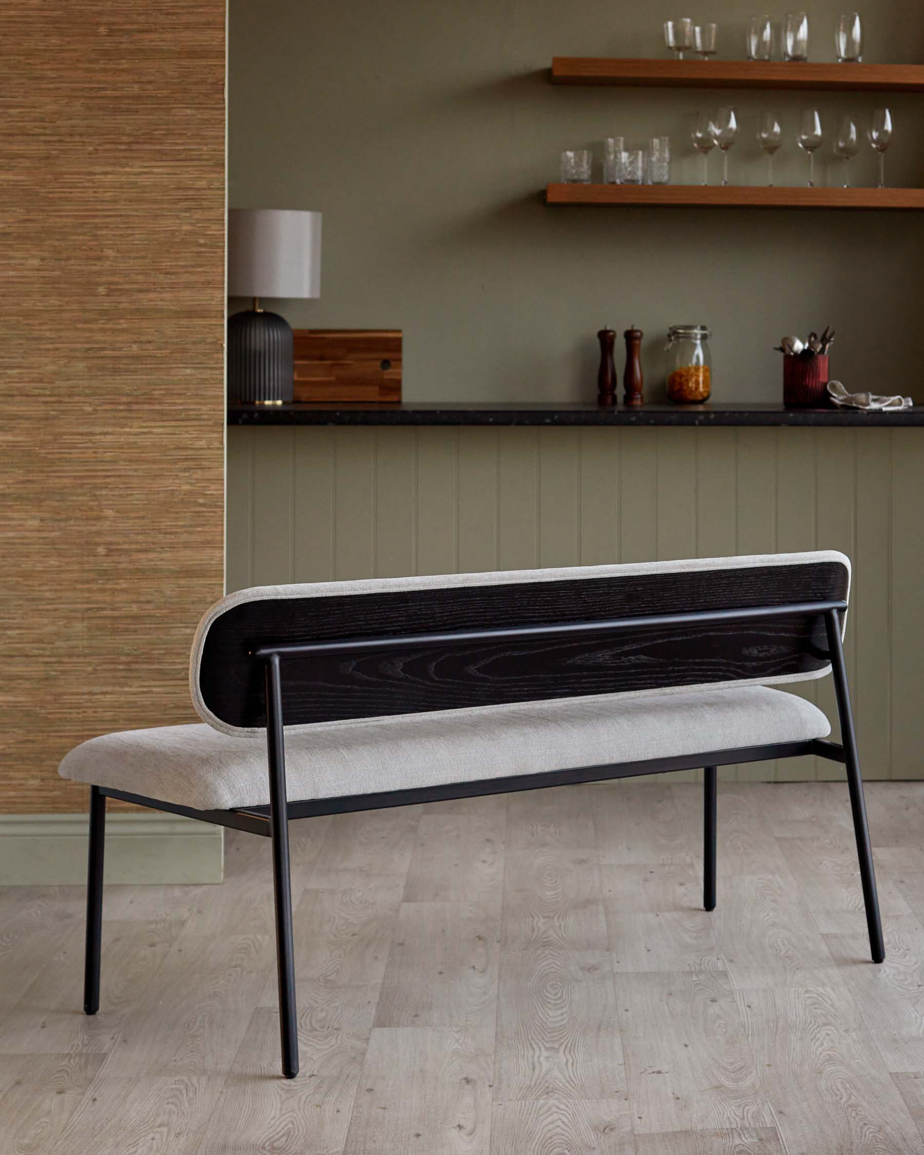 Sleek black metal-framed bench with a soft gray upholstered seat and a rounded wooden backrest, perfect for modern interiors.