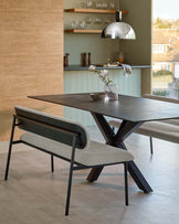 Stylish dining table with a dark top and angled legs, paired with a modern bench featuring soft upholstery and a sleek design.