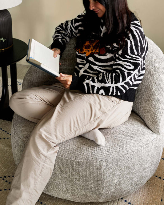 Cozy oversized fabric chair in a light gray hue, paired with a sleek black side table featuring a lamp.