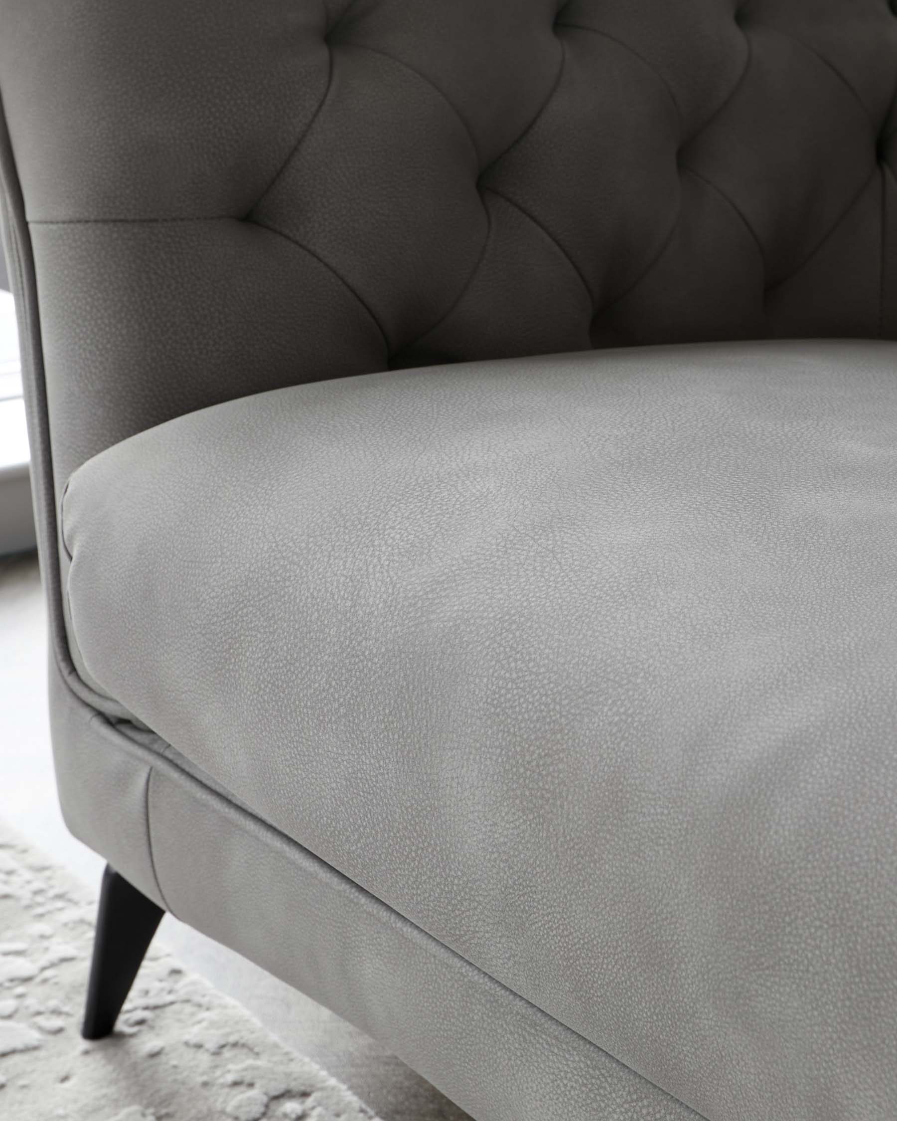 Elegant gray upholstered chaise lounge with tufted detailing and sleek black legs, ideal for modern living spaces.