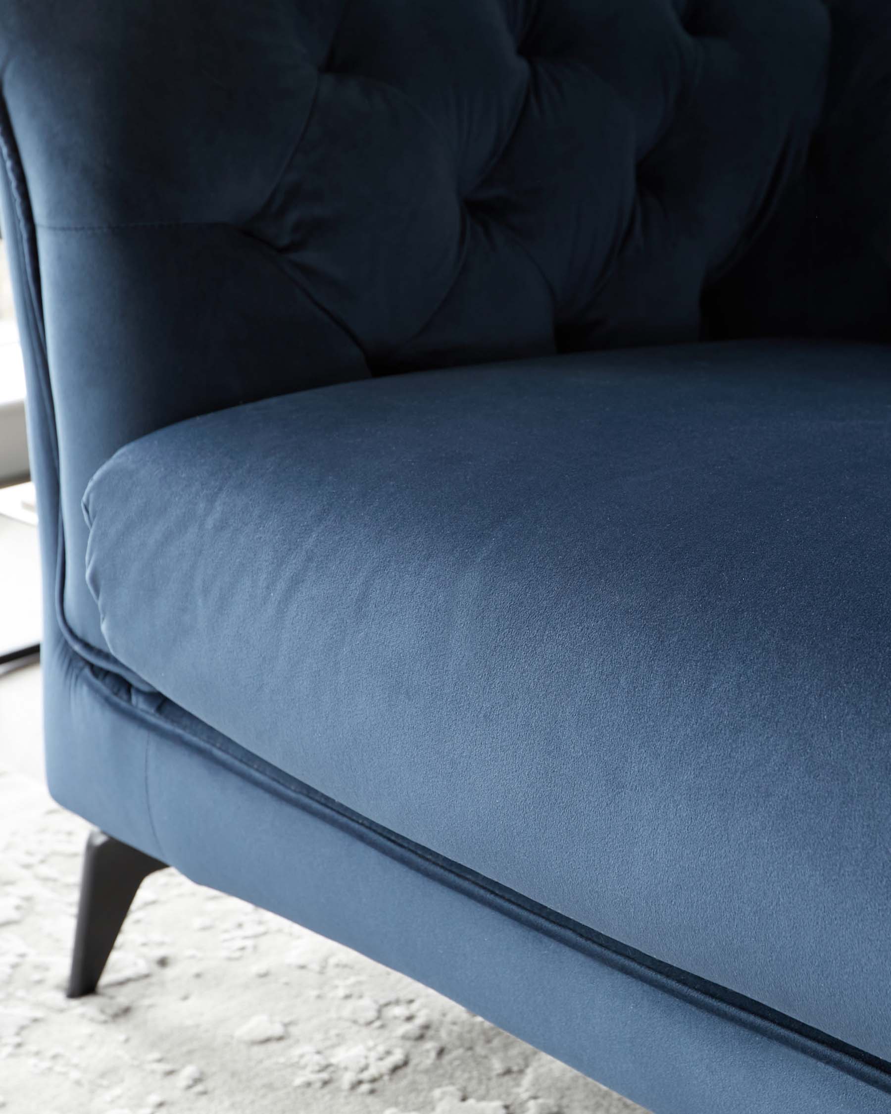 Elegant tufted blue velvet upholstery with a plush seat, supported by sleek dark wooden legs. Perfect for a modern living space.