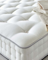 Luxurious white tufted mattress with a soft texture, accompanied by neatly folded blankets in beige and cream tones.