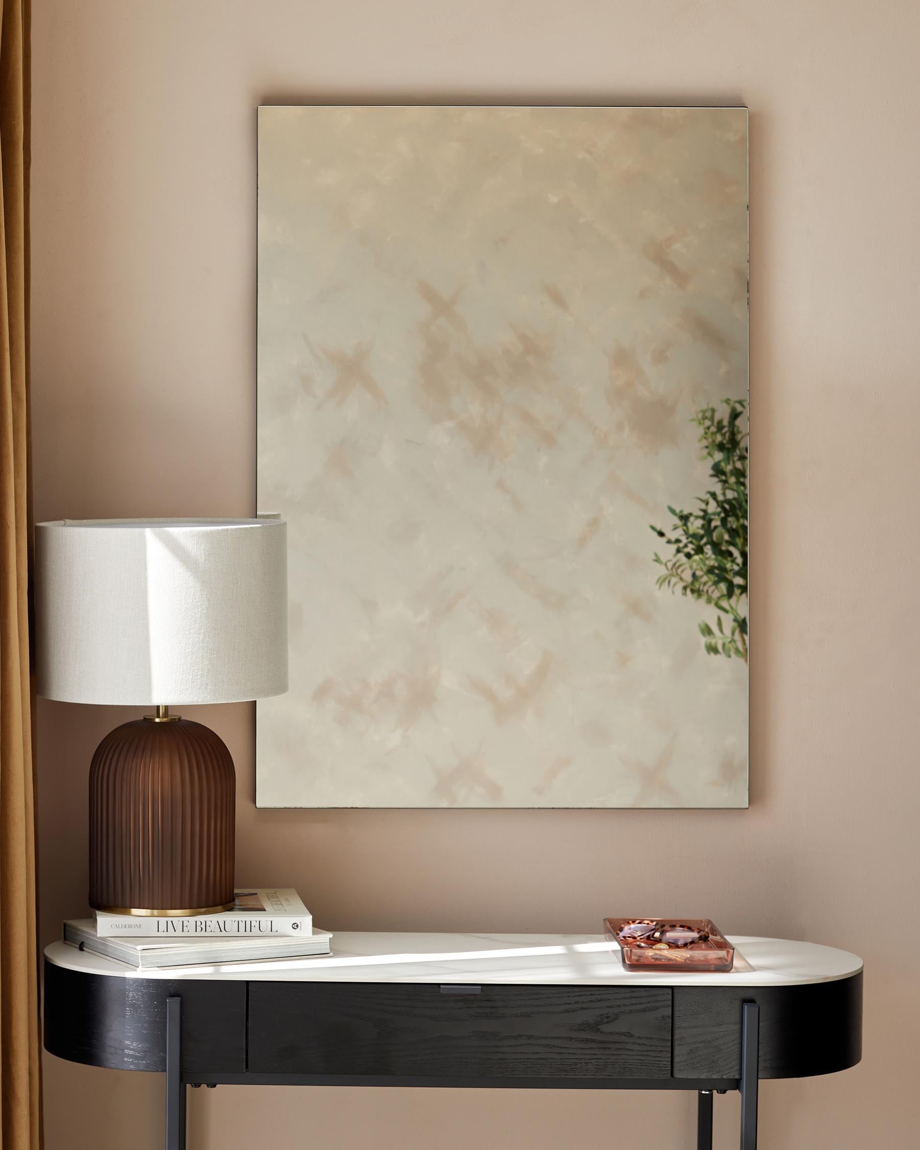 Elegant black and white console table with a curved silhouette and a glossy finish, accented with a cylindrical brown lamp with a white shade, placed beside a stack of hardcover books.