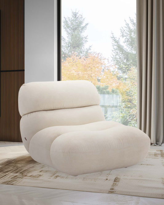 A plush, cream-colored lounge chair with a modern design, featuring contoured shapes and a cozy, inviting appearance.