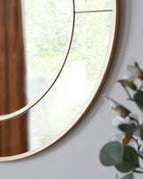 A modern round wall mirror with a slim golden frame.