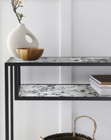 Modern console table with a marble top, wooden bowl, textured vase, stacked books, and a woven basket.