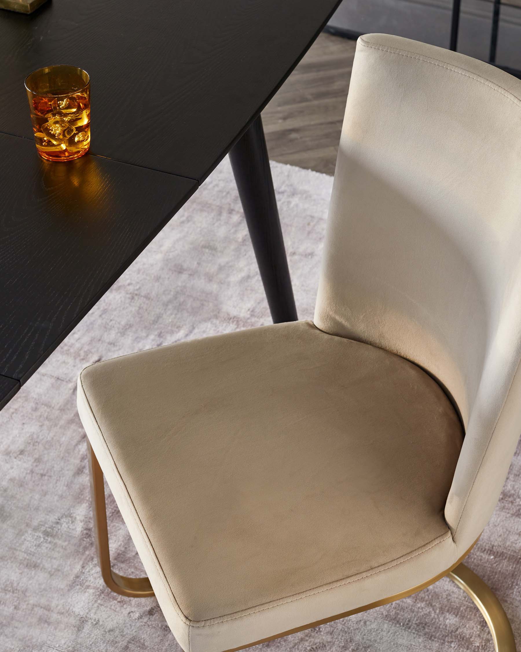 Elegant modern dining chair with a curved backrest and a gold metal frame, paired with a sleek black dining table, on a plush area rug.