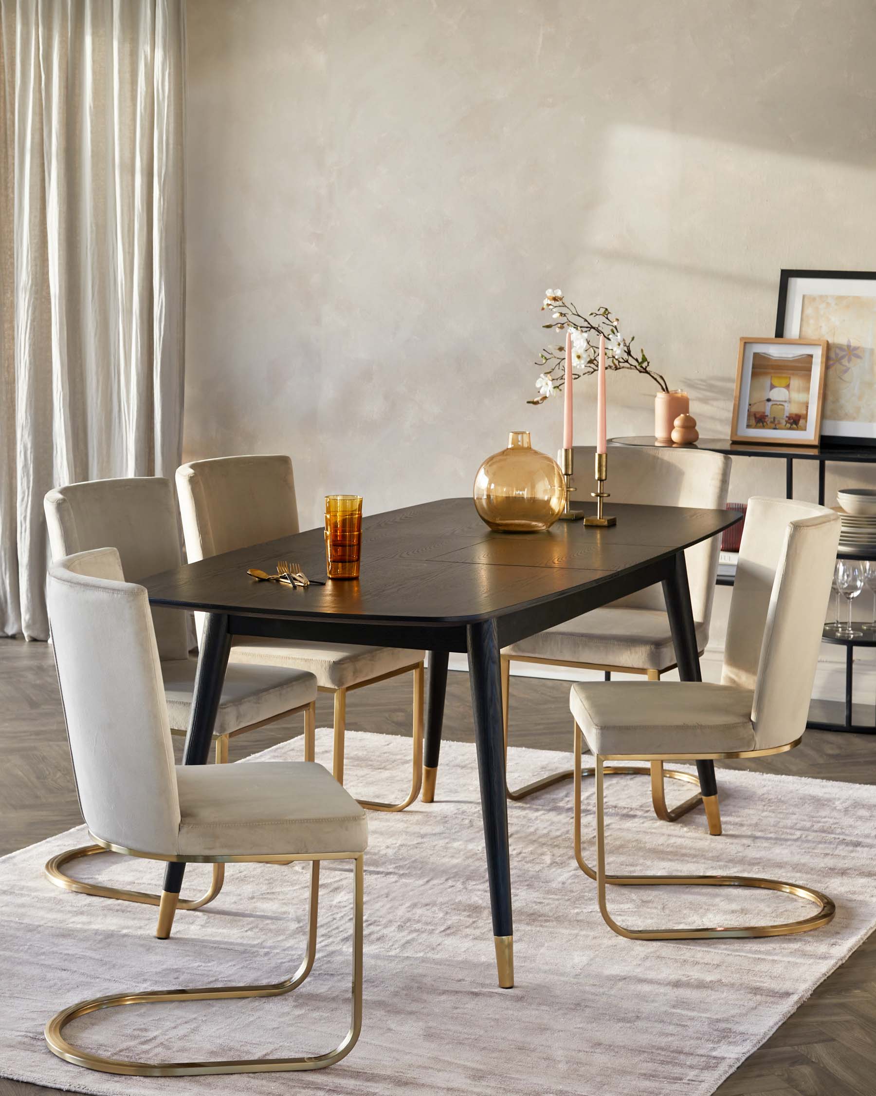 Elegant dining room set featuring a dark wooden table with sleek, black legs accented with gold tips. Surrounded by four cream-colored upholstered chairs with unique gold-finished metal base frames in a curved design.