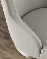 Elegant cream-colored chair with soft leather upholstery, featuring sleek stitching and a stylish metallic base.