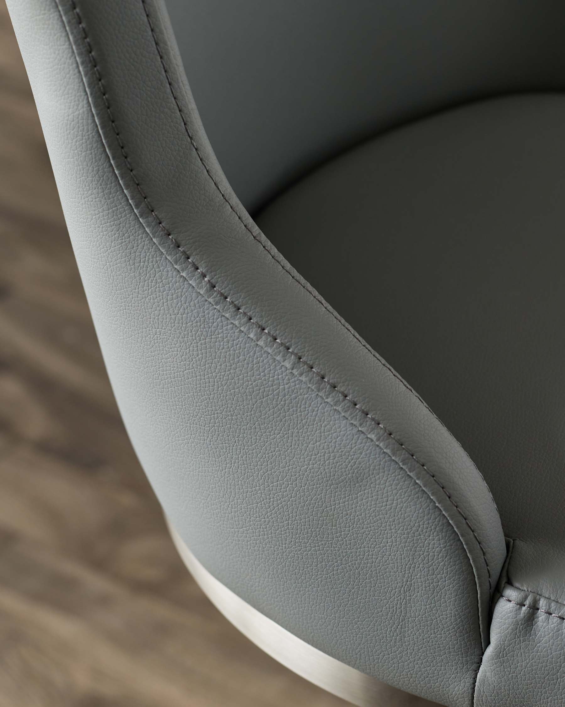 Stylish grey leather chair with sleek, rounded edges and subtle stitching, resting on a metal base. Perfect for modern spaces.