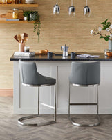 Two sleek, gray bar stools with metallic frames at a modern kitchen island, complemented by stylish kitchen decor.