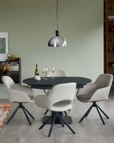 Round black dining table with four light beige chairs featuring curved backs and dark legs, topped by a sleek pendant lamp.