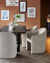 A sleek black dining table accompanied by curved, upholstered cream chairs, accented with floral decor and framed artwork.