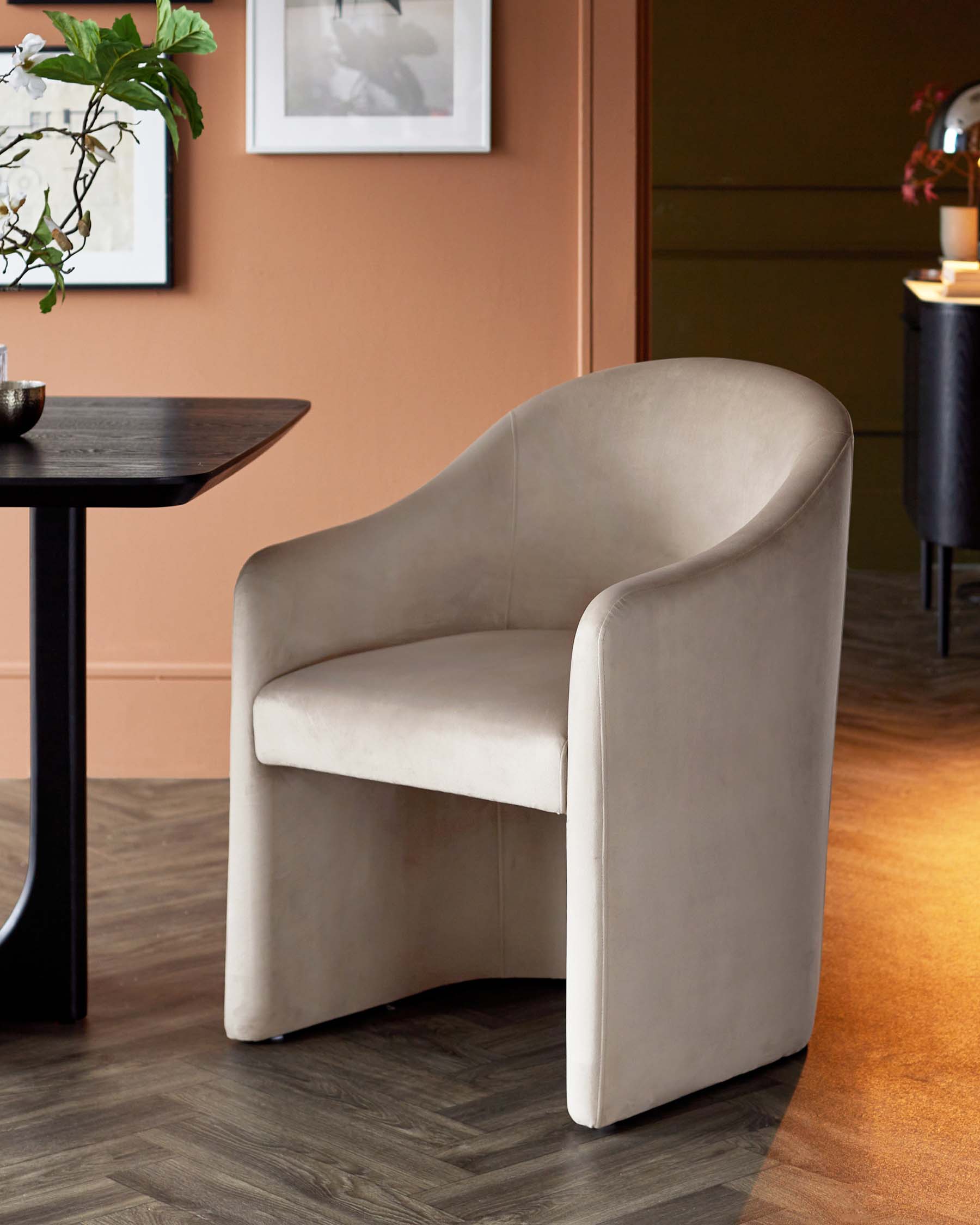 Stylish beige armchair with a minimalist design, featuring curved sides and a soft upholstery, paired with a modern black table.