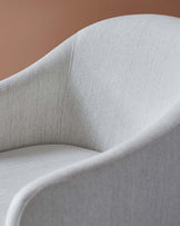 Curved, softly upholstered armchair in light gray fabric, featuring smooth lines and a minimalist design.