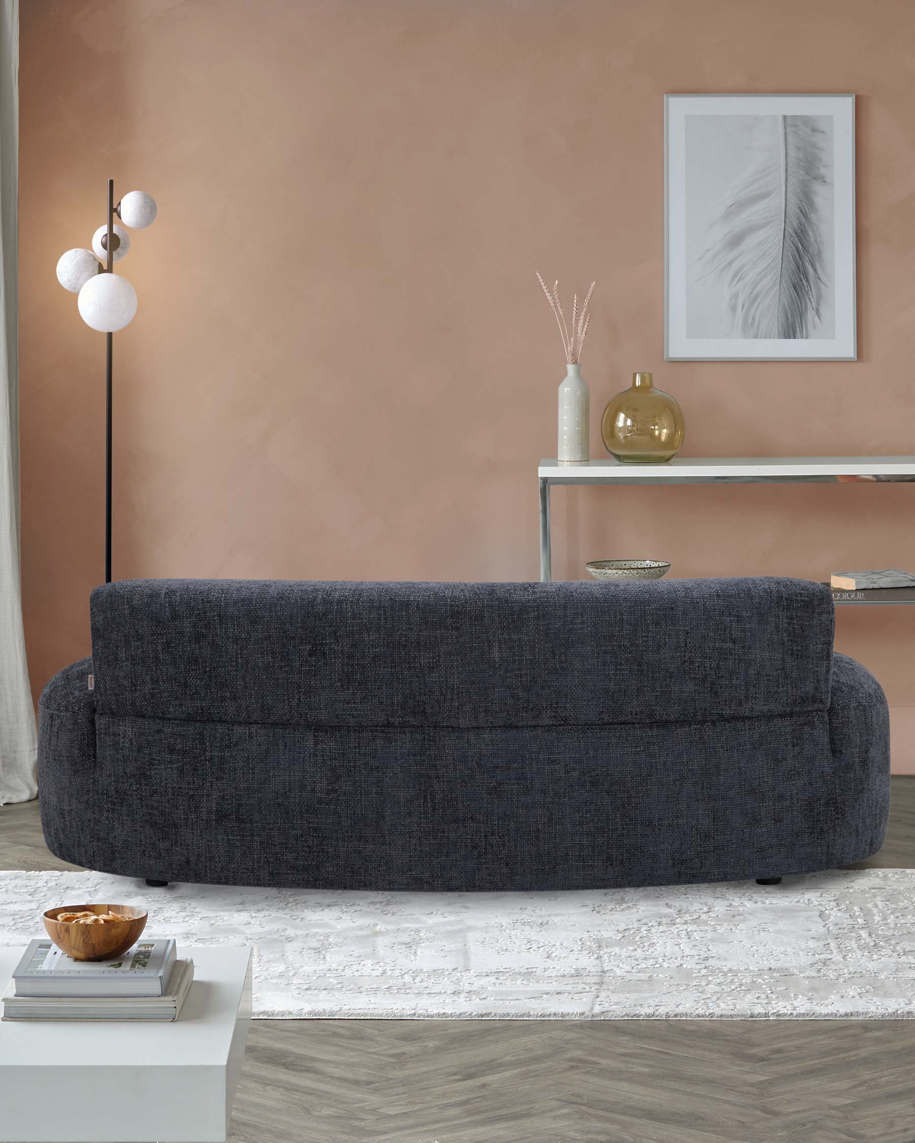 Modern furniture featuring a curved dark gray sofa, minimalist shelf, decorative vase, and stylish floor lamp in a cozy setting.