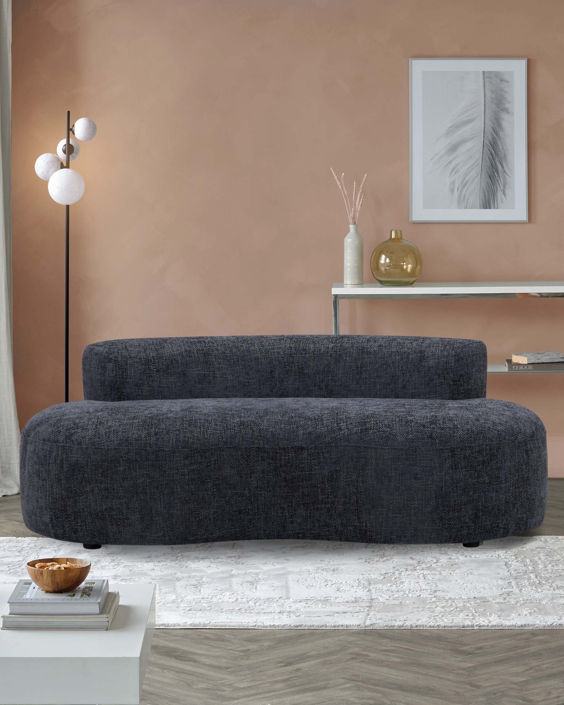 A modern dark gray curved sofa, accompanied by a sleek lamp, minimalist side table, decorative vases, and a neutral rug.