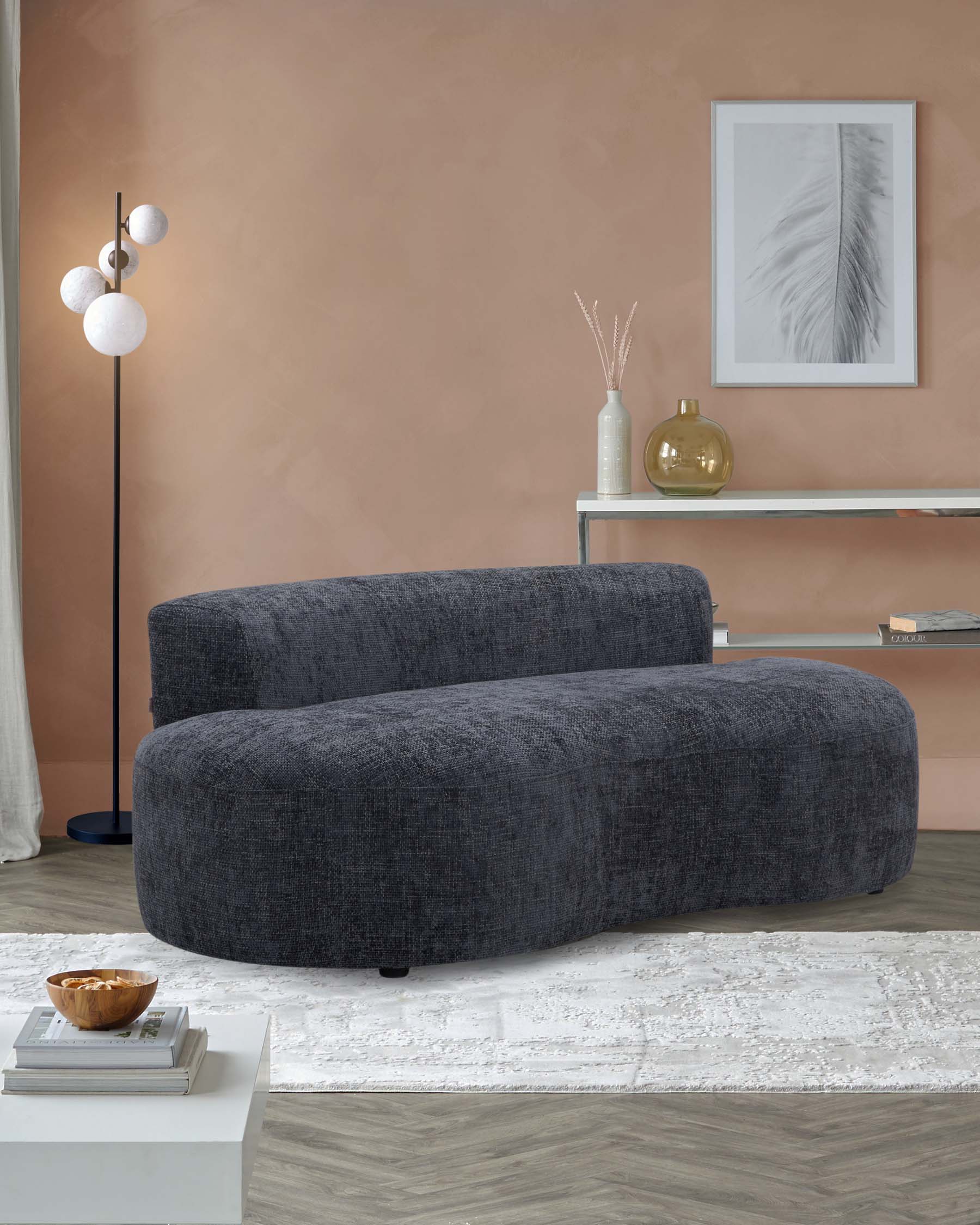 Curvy gray sofa, minimalist side table with decorative items, modern floor lamp, and light rug against a soft pink wall.