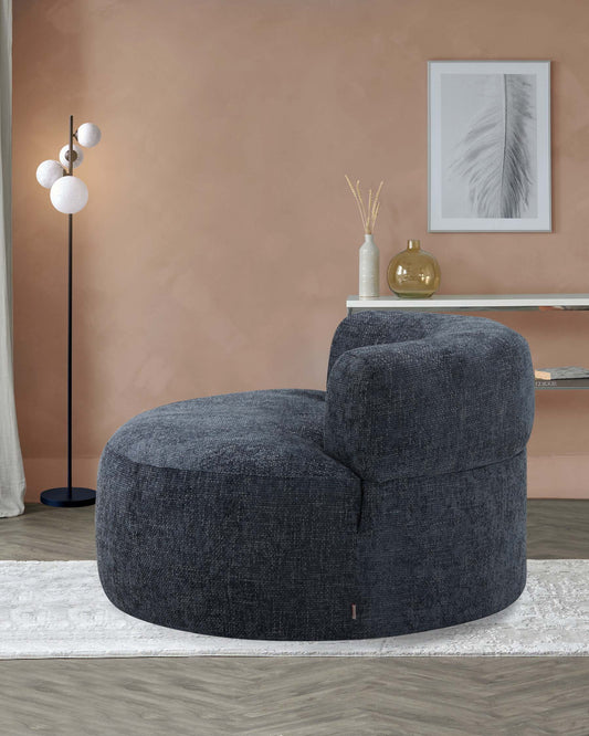 Round, plush dark gray chair, modern floor lamp with globe shades, minimalist table decor, and soft area rug.