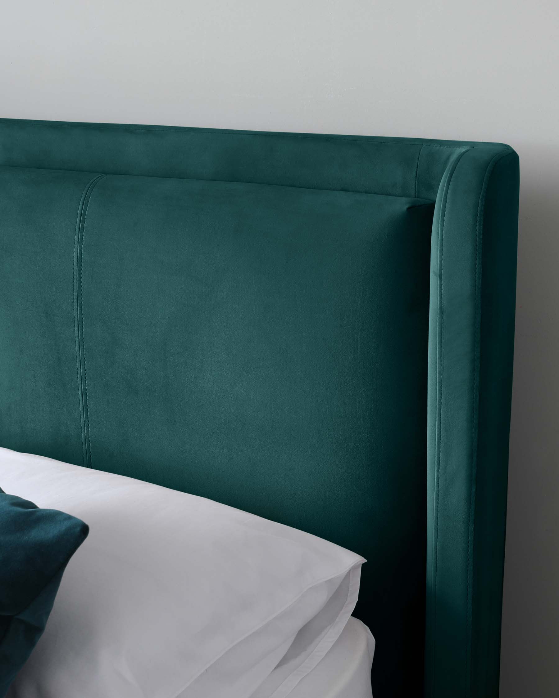 Elegant teal upholstered headboard with a smooth curved top and subtle seam detailing, paired with crisp white bed linen.