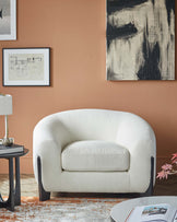 Cozy white upholstered armchair with curved design, paired with a modern side table and decorative accents against a warm backdrop.