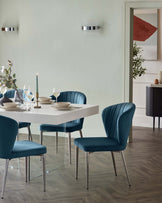 Modern dining room furniture set featuring a sleek white rectangular table with a minimalist design and four elegant teal blue upholstered chairs with a curved backrest and slender metal legs.