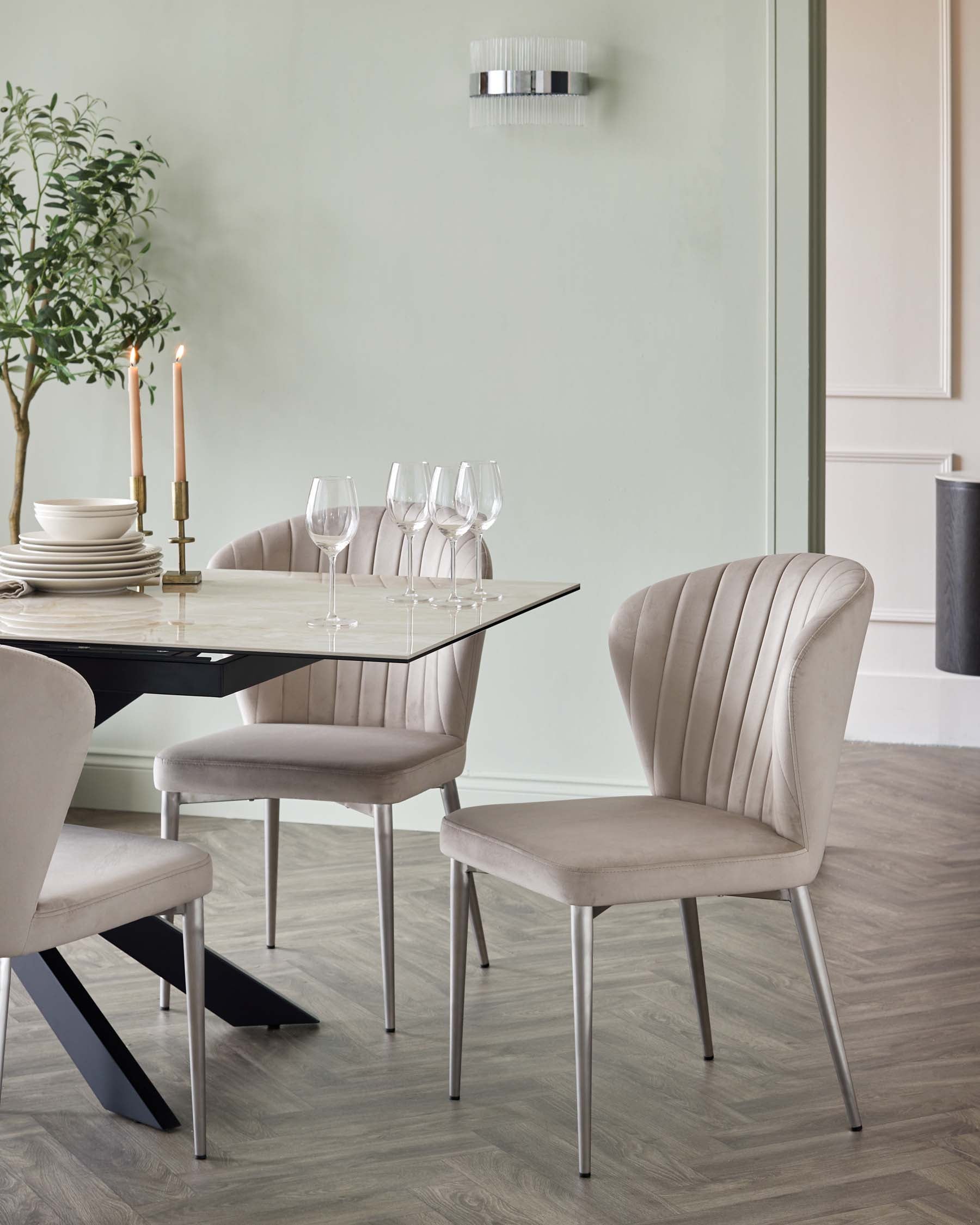 Modern dining set with a rectangular marble-top table featuring angled black legs, accompanied by four plush velvet-upholstered chairs with channel-back design and slender metal legs.