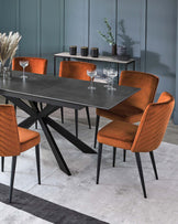 Modern dining set featuring a sleek black table and stylish orange velvet chairs, accented with decorative vases on a console.