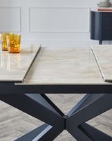 A stylish dining table with a marble top and a geometric black base, featuring glass drinkware on display.