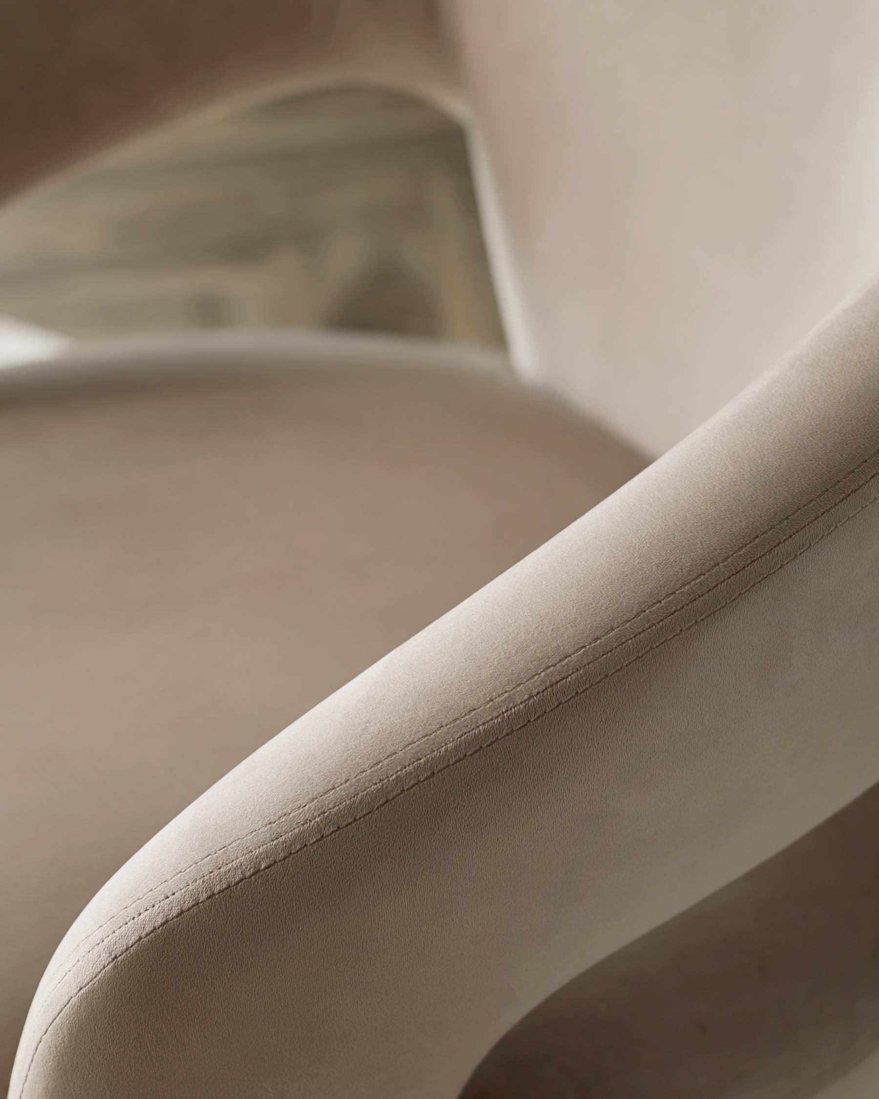 Elegant beige upholstered chair with soft curves and smooth seams, showcasing a modern design perfect for stylish interiors.