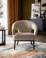 Elegant beige accent chair with curved arms and sleek black legs, paired with a round black side table on a textured rug.