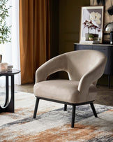 A plush beige accent chair with curved arms, paired with a sleek black side table, on a colorful area rug.