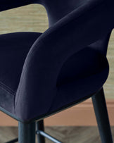 Elegant navy blue upholstered chair with a modern design, featuring sleek armrests and a sturdy black metal base.