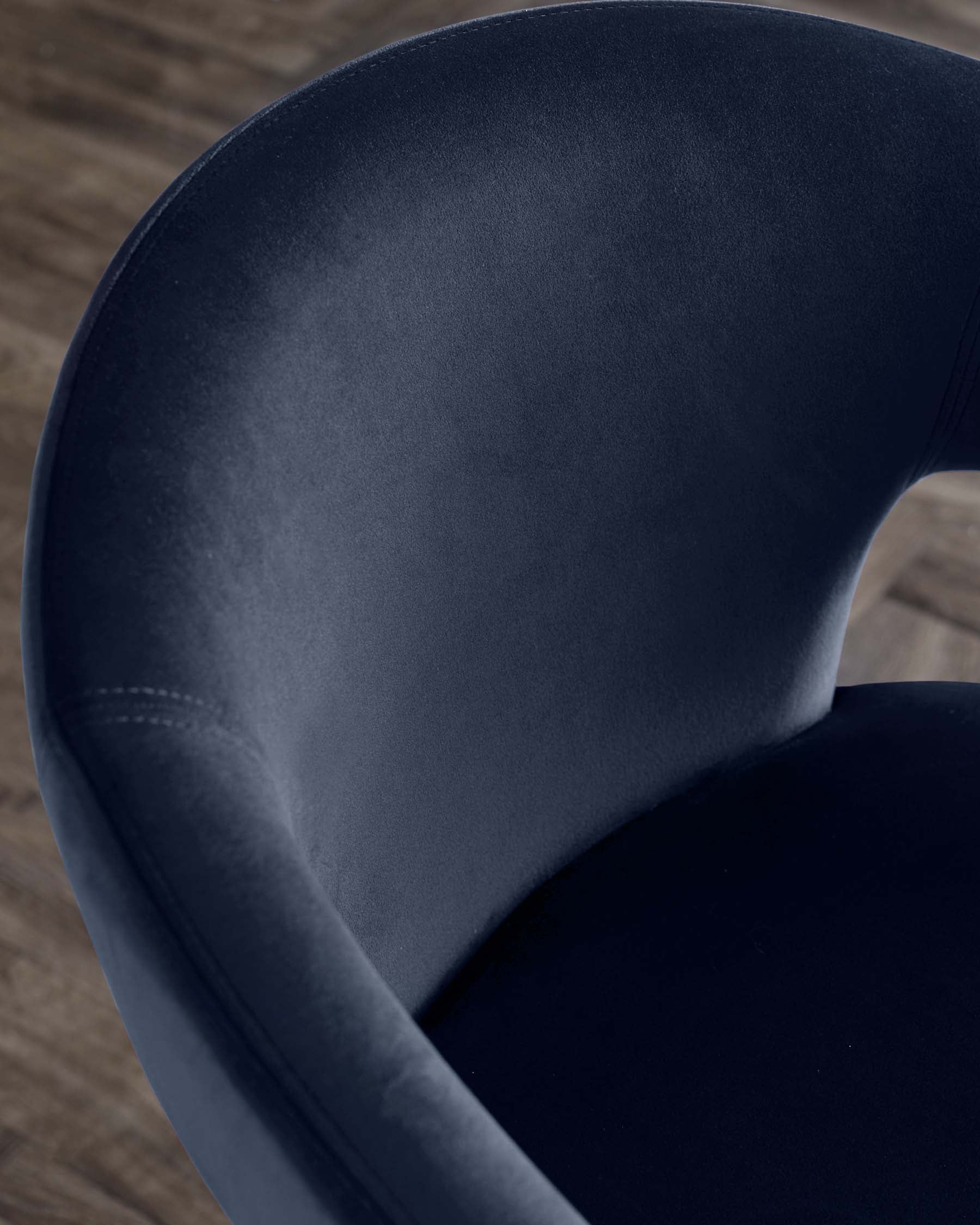 Elegant navy velvet chair with a smooth, rounded backrest, showcasing modern design and luxurious texture.