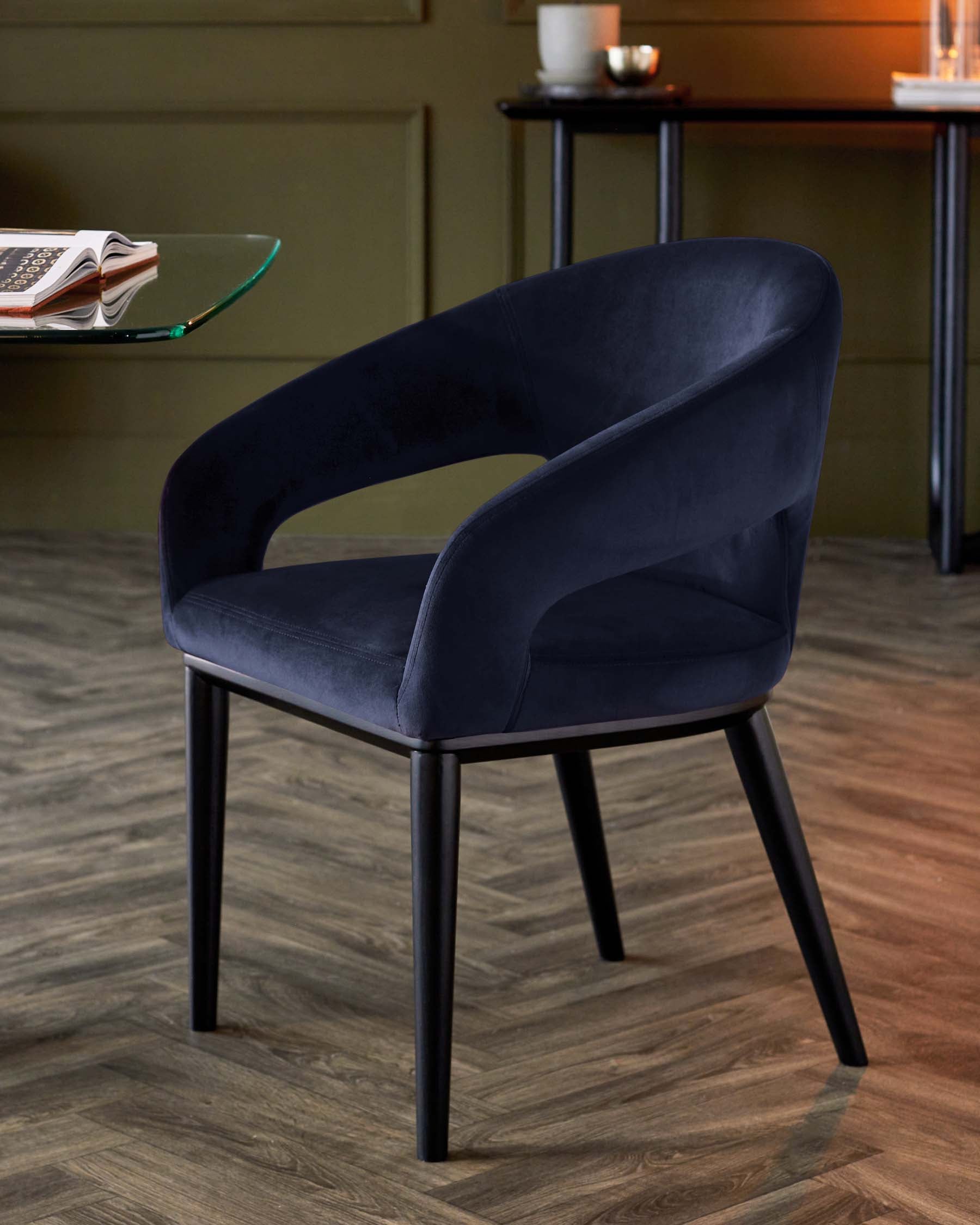 Stylish navy blue upholstered chair with rounded backrests and sleek black legs, set against a warm, inviting backdrop.