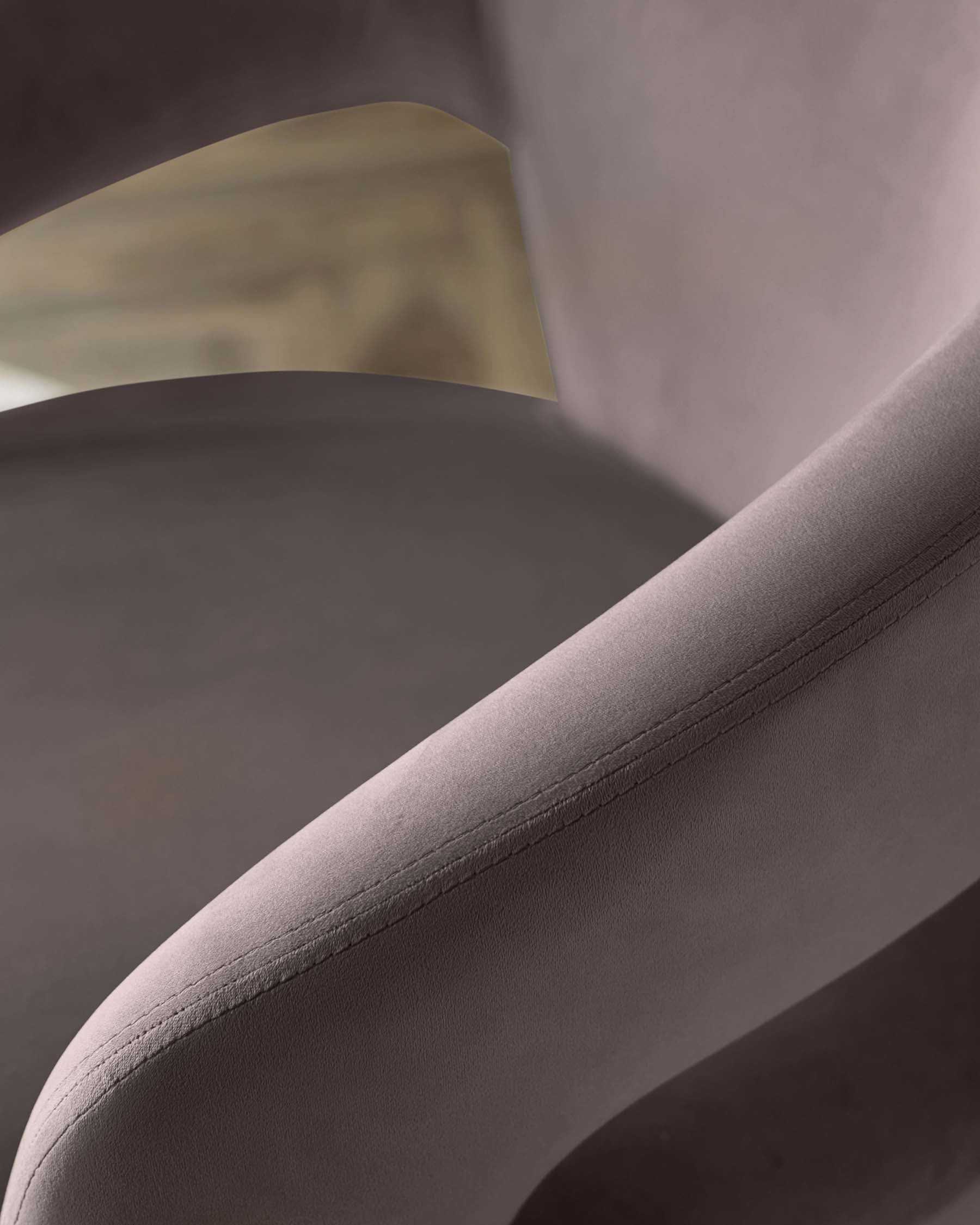 Close-up of a sleek, modern chair with a soft upholstered seat and armrest, showcasing minimalist design and subtle stitching.