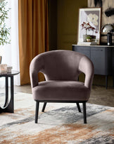 Stylish curved armchair in soft taupe fabric, complemented by black legs and set against a modern, textured rug.