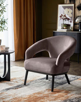 Stylish gray upholstered chair with curved backrest and black legs, paired with a round side table on a textured rug.