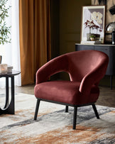 A plush, burgundy accent chair with sleek black legs, paired with a round coffee table on a patterned area rug.