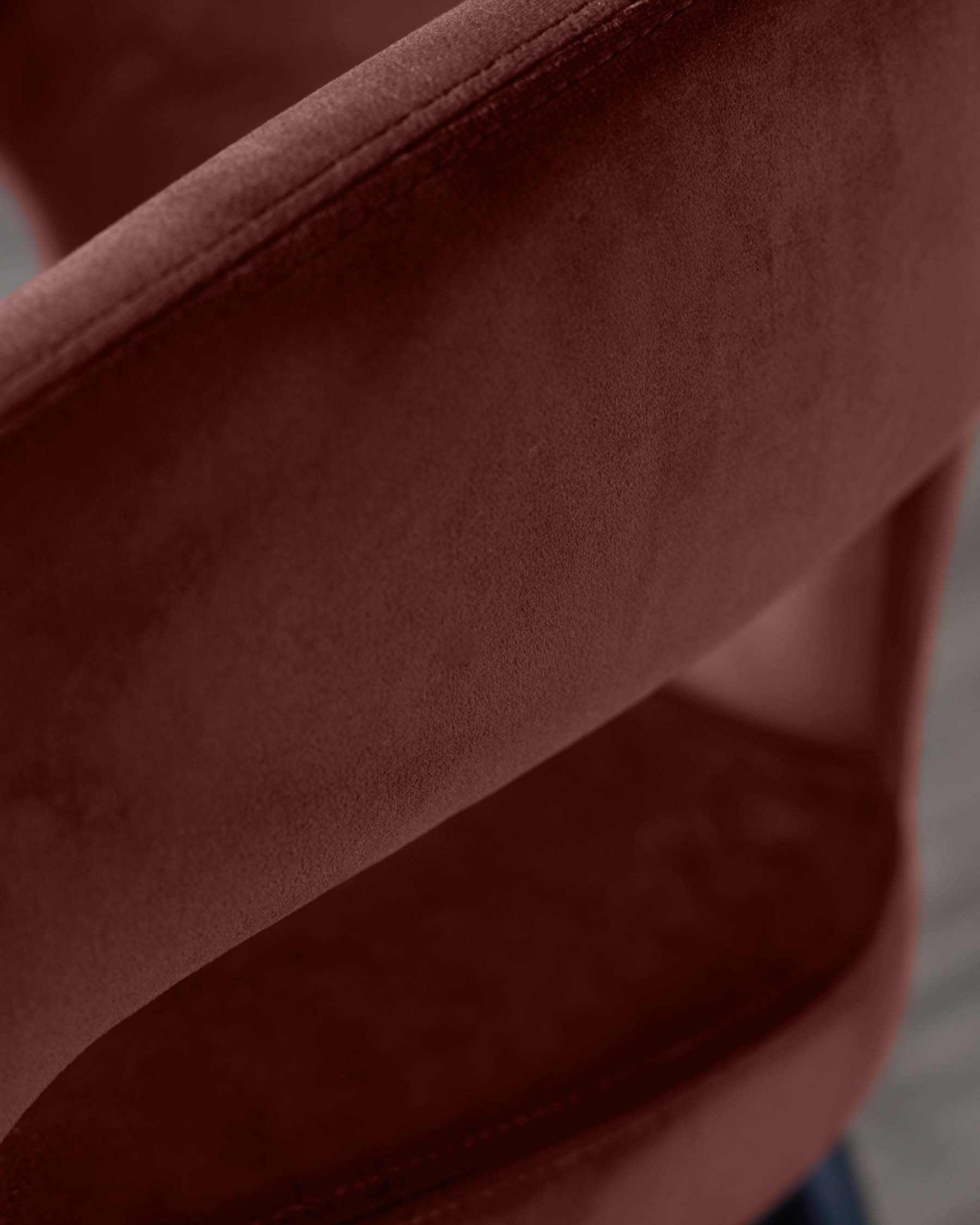 Close-up of a modern chair with a rich burgundy velvet fabric, featuring smooth curves and clean stitching for a stylish look.