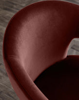 Luxurious burgundy velvet accent chair with a smooth, rounded back and cushioned seat, ideal for stylish living spaces.