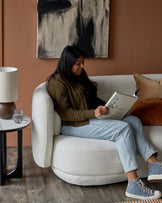 A cozy round white sofa, a stylish marble-top side table, and a modern lamp, creating a warm, inviting space.