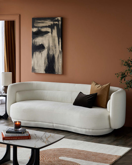 Curved white sofa with plush cushions, marble-top coffee table, and a stylish area rug, set against a warm, earthy wall.