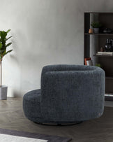 A contemporary, plush, dark teal swivel chair paired with a modern black shelf displaying decor and greenery.