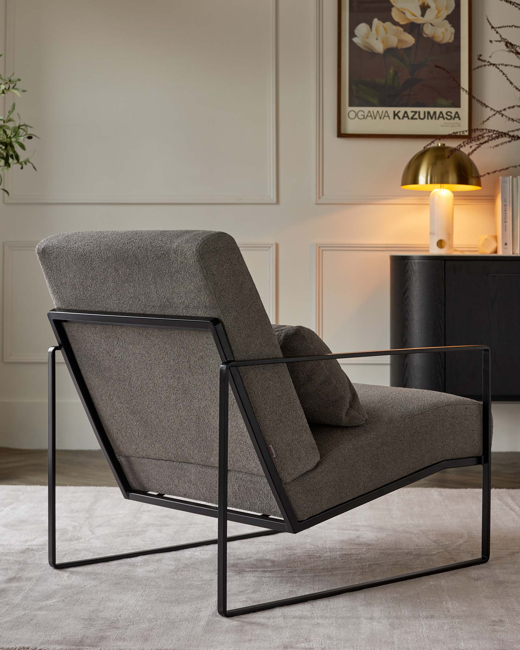 A modern grey upholstered accent chair with a unique black metal frame, featuring clean lines and an invitingly angled back cushion, set in an elegant living room setting.