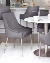 Stylish gray dining chairs with sleek metal legs and a round white table, set on a light rug, creating a modern dining area.